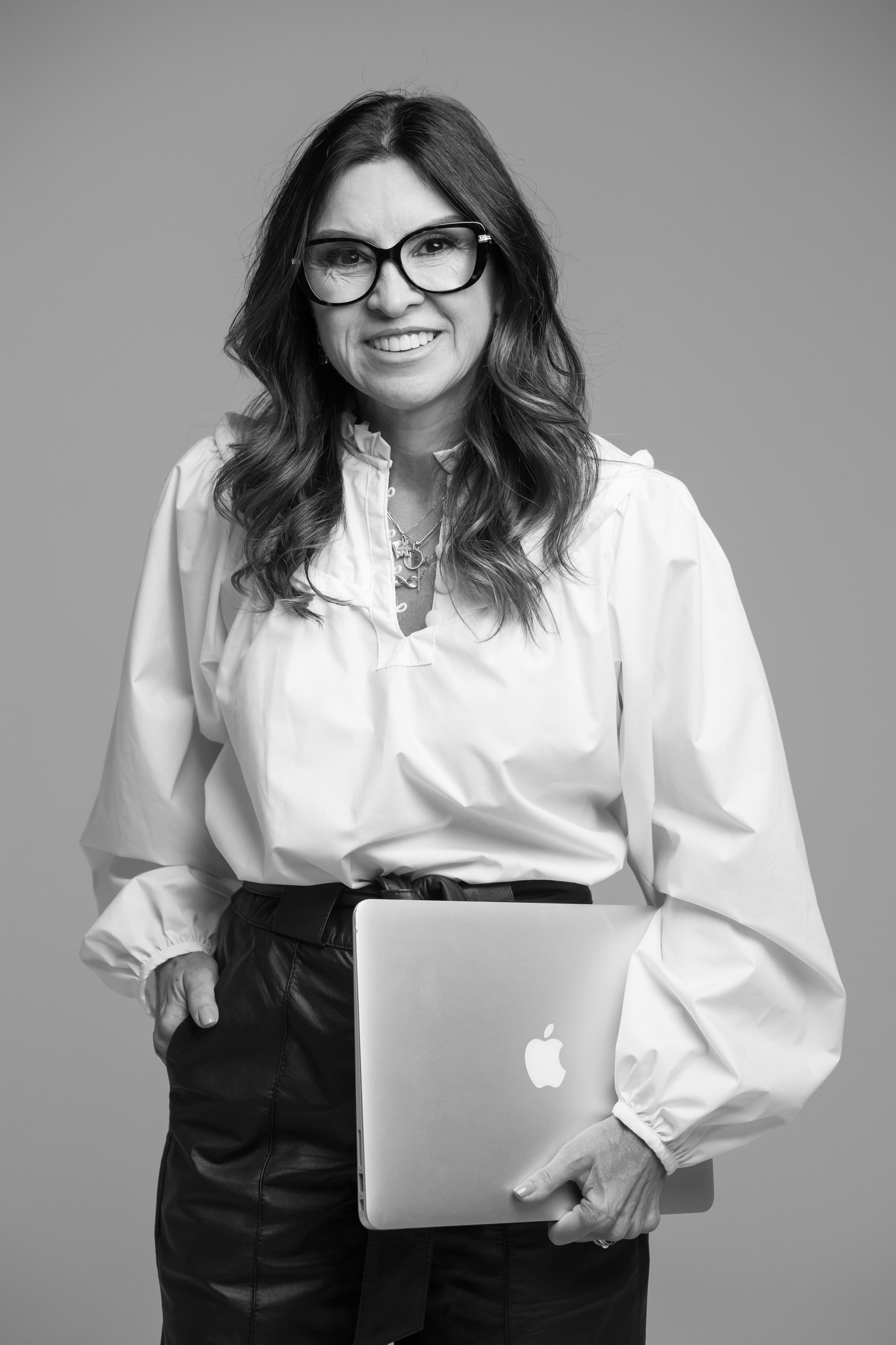 Claudia em pé com laptop, posicionamento consultivo